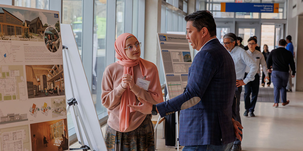 A male graduate student presenting his research in front of a small crowd of people