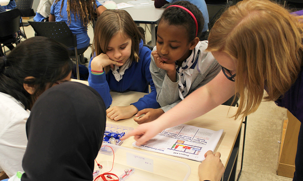 Teacher instructs young students at a table