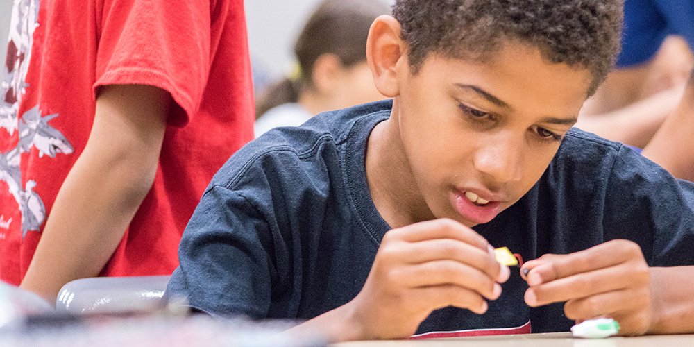 A young student working with a small electronic device