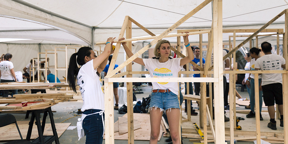 Two Toronto Metropolitan University students working outside with wood to build their Timberfever structure for the competition