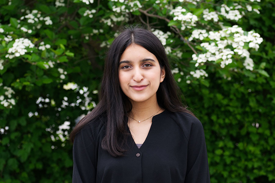 Iman Cheema smiling against a floral back drop