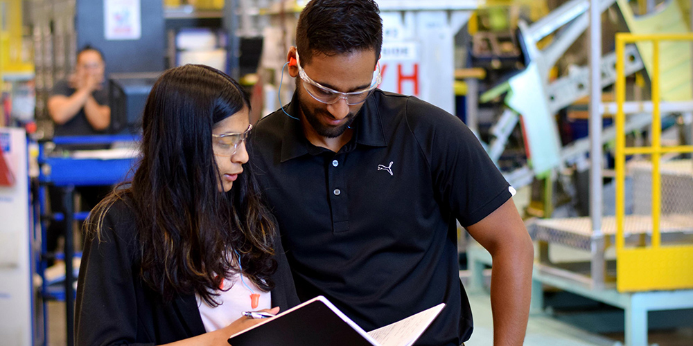 Man and woman discuss a document in a industrial facility