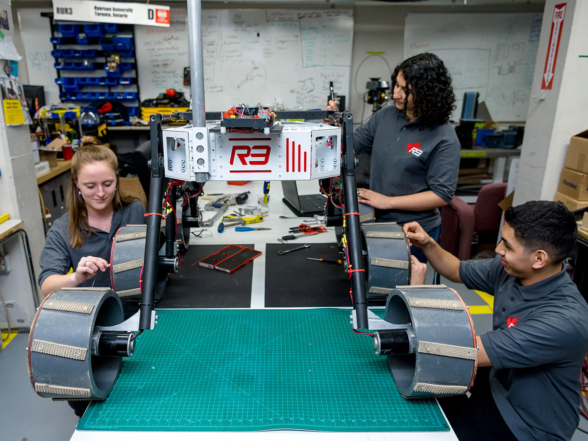 Three students of the robotics team work on mars rover