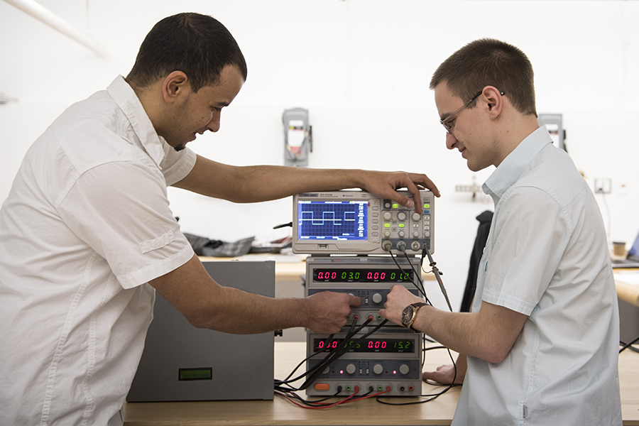 Two male students work on a machine