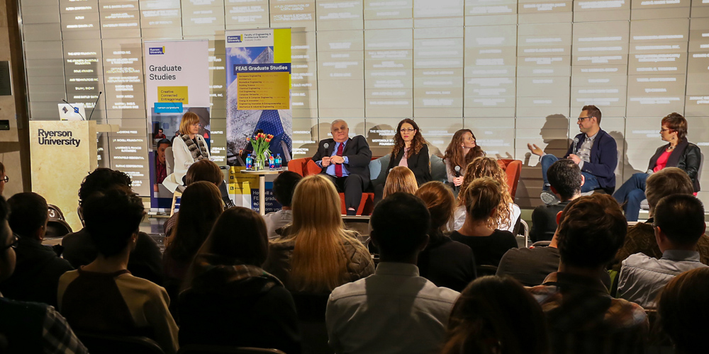 A panel of people talking in front of a crowd of graduate students