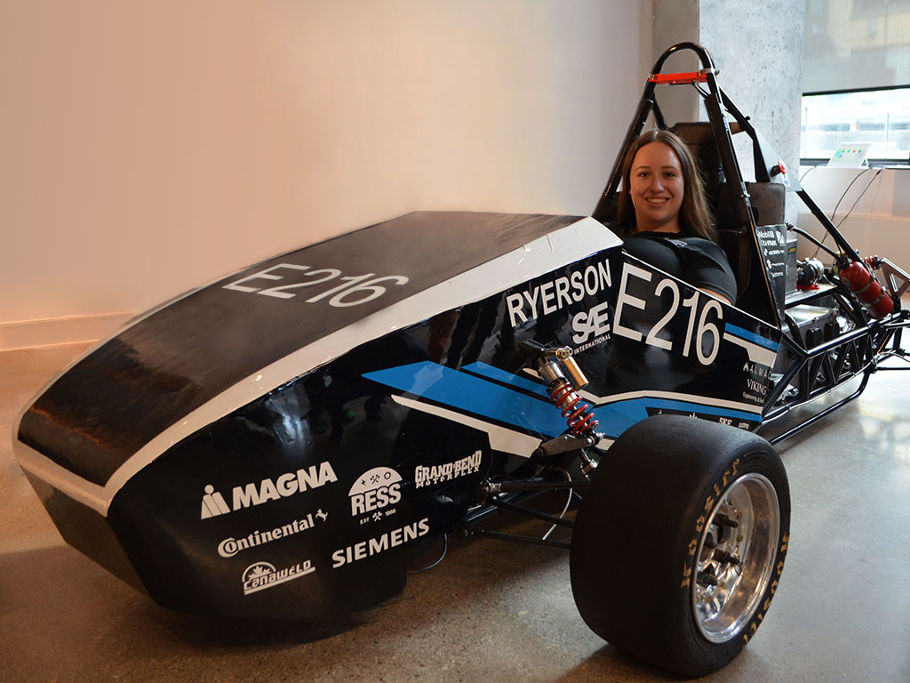 alumna Erica Attard (BEng Mechanical ‘22) sits in the Formula Racing team's new electric car - E216