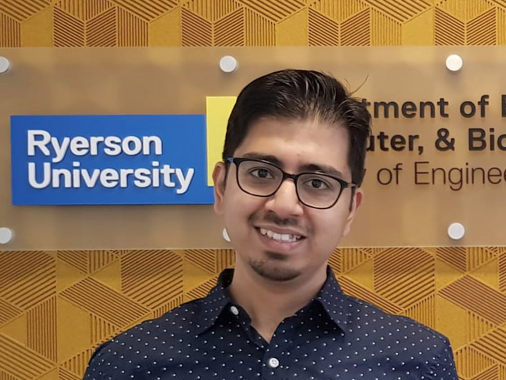 Owais Khan stands in front of an indoor Toronto Metropolitan University Department of Electrical, Computer, & Biomedical Engineering sign