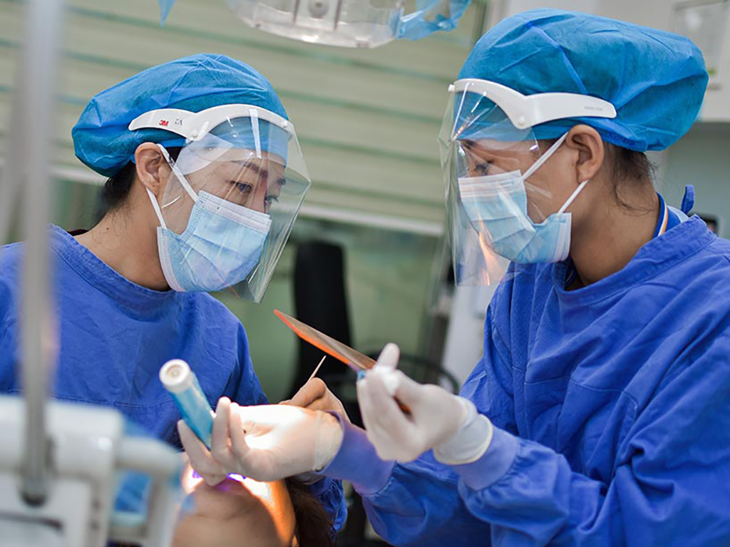 Two nurses wearing Personal Protective Equipment (PPE) work together