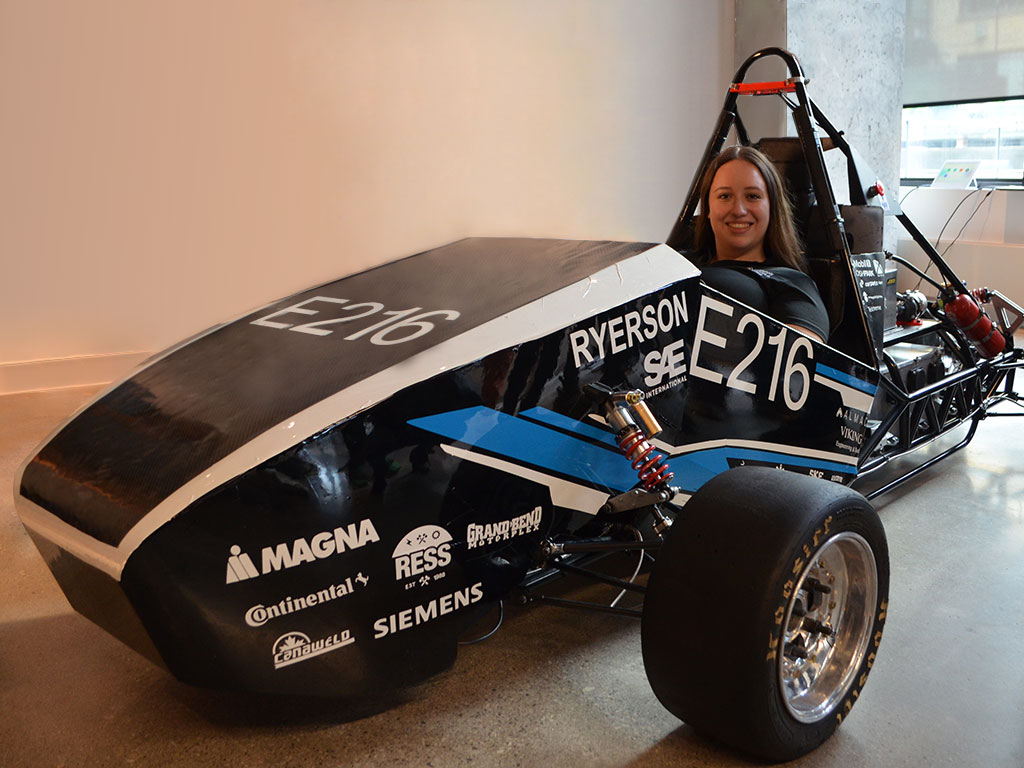 Erica Attard sits in the Formula Racing team's electric racing car E216 smiling