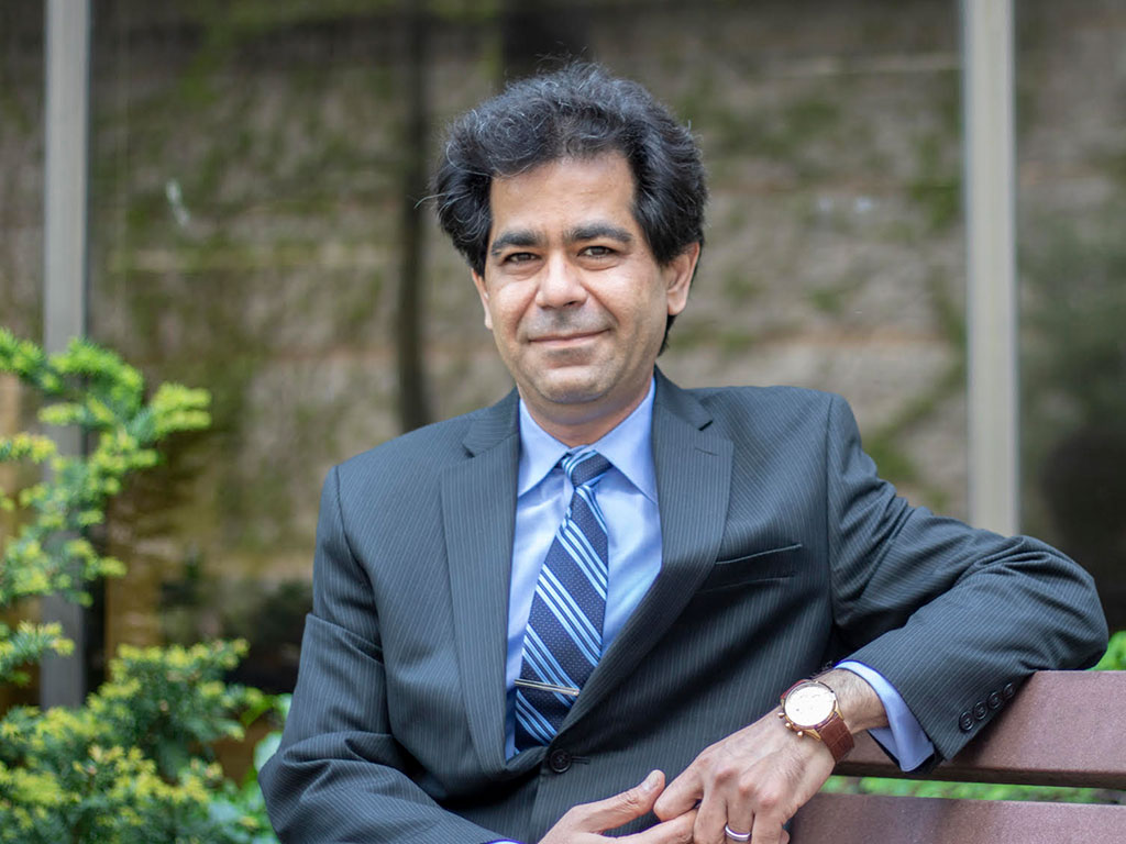 Kourosh Zareinia smiling while sitting on a bench