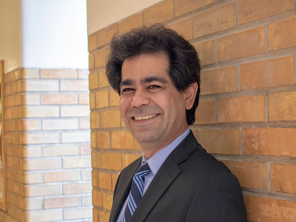 Professor Kourosh Zareinia smiling in a well-lit brick hallway