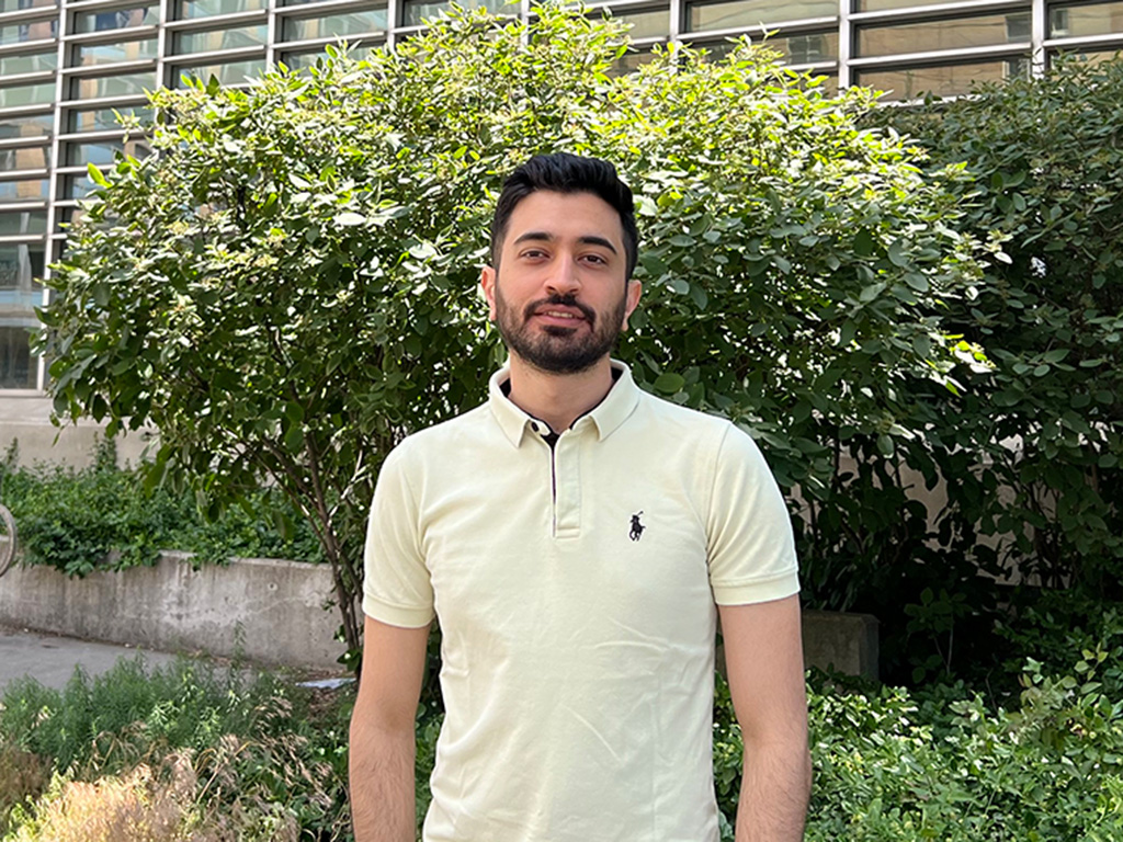 Pooyan Nayyeri smiling in front of a large bush