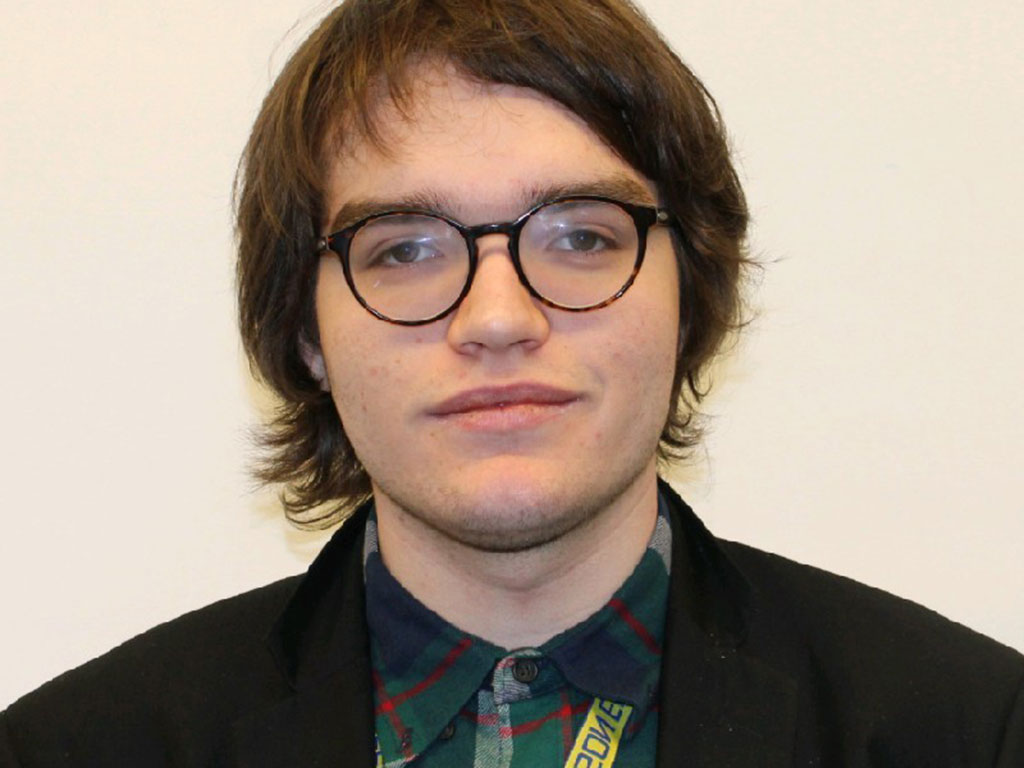 Christian Richards looks at the camera wearing glasses, a green shirt a black blazer