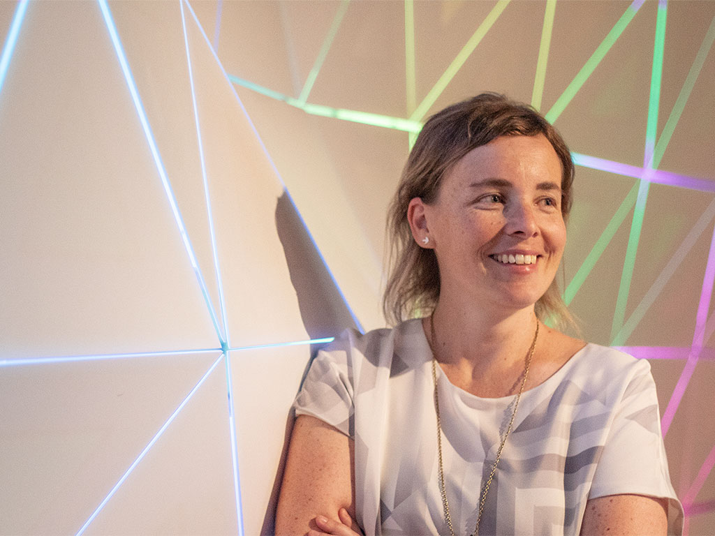 Department of Architectural Science professor Terri Peters stands against a geometrically shaped wall smiling