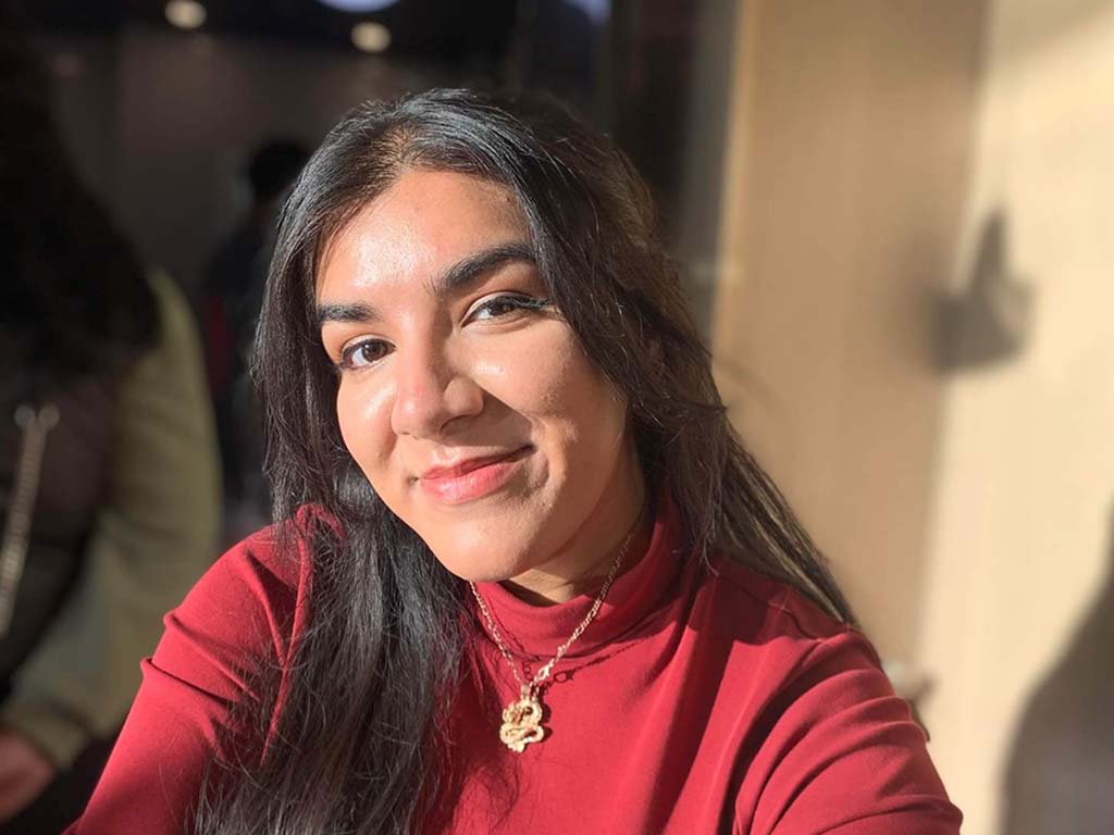 Tanzina Nowshin smiles at the camera wearing a red turtleneck