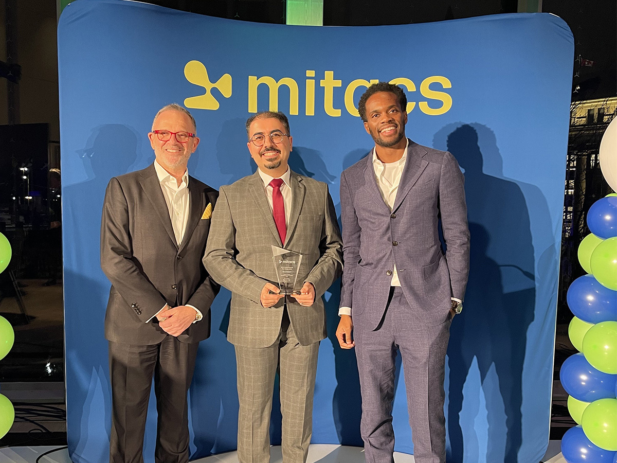 a group standing in front of Mitacs Award