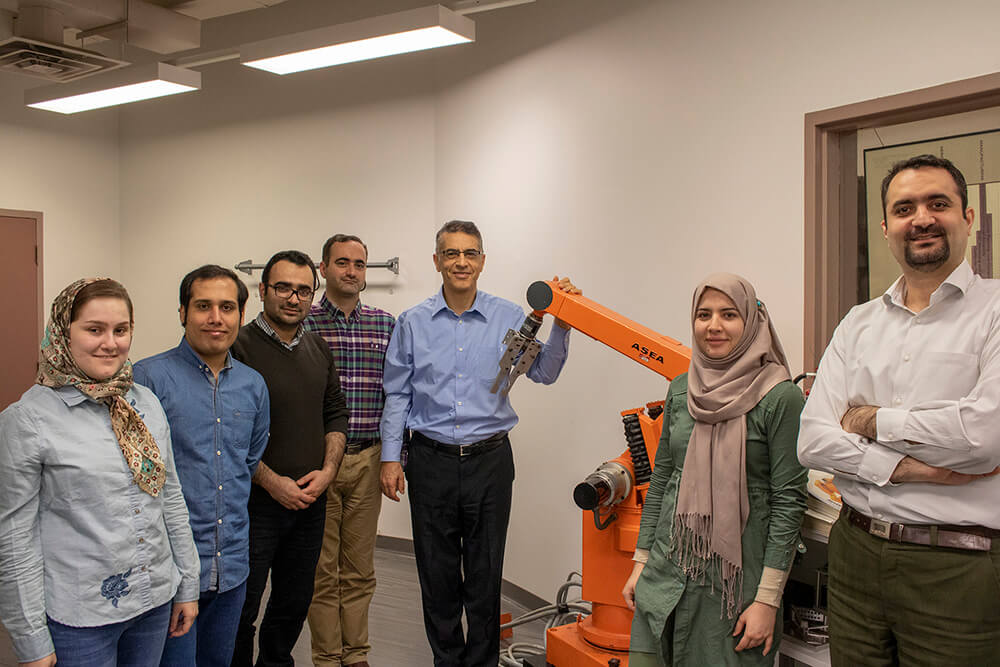 group photo of people around a robotic