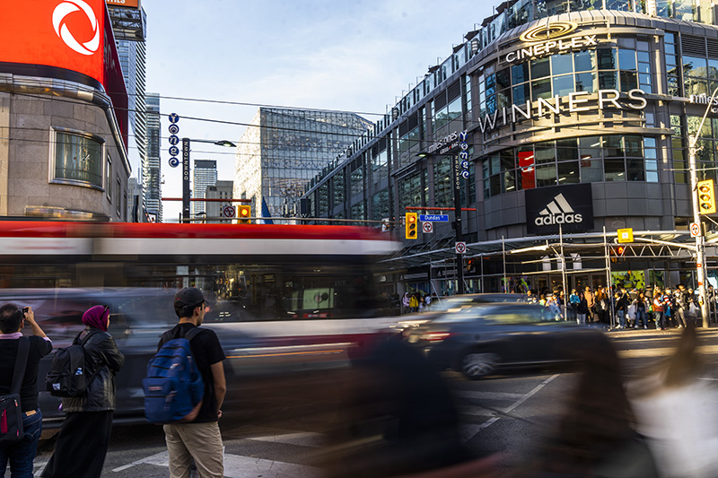 A red and white street car passing pedestrians in downtown Toronto, the home of Toronto Metropolitan University. 