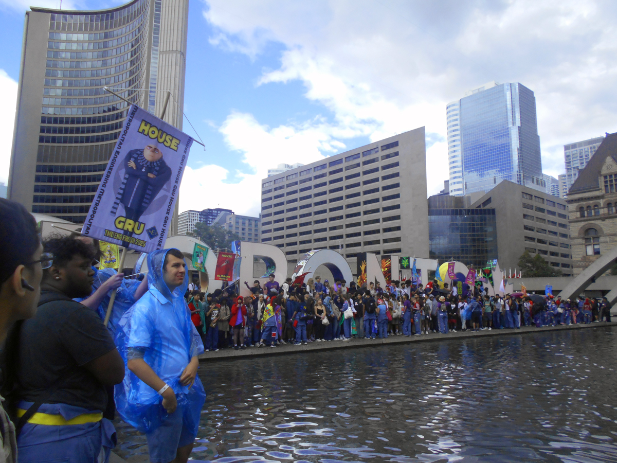 Group of smiling students holding frosh banners outside of Toronto’s City Hall. 