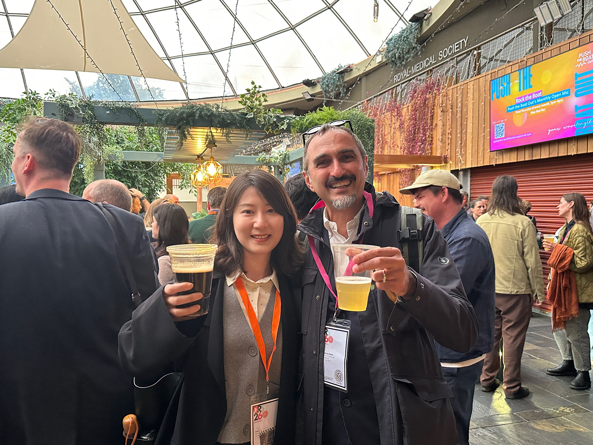 Yaxin Jiang holding up a drink with Paolo Ciuccarelli inside at the DRS conference in Scotland. 
