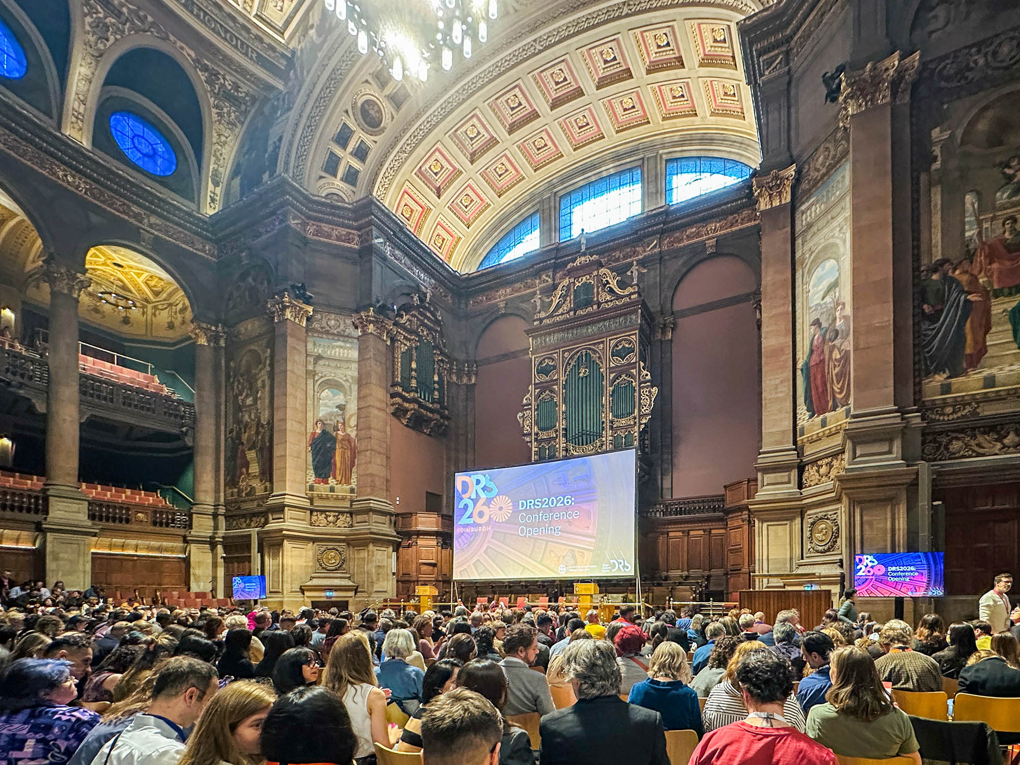 A group of conference attendees looking at projection in the University of Edinburgh’s McEwan Hall.