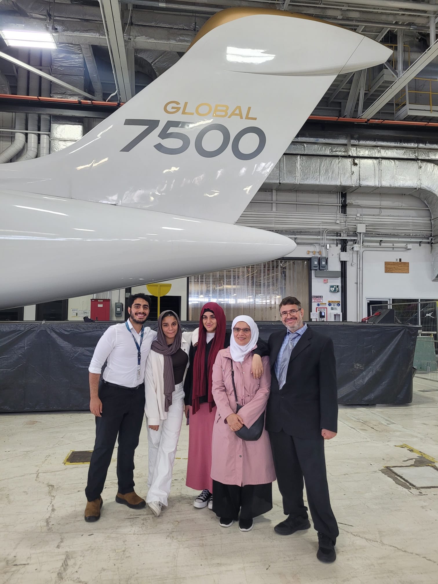 Ahmed Negm standing with family members next to business jet.
