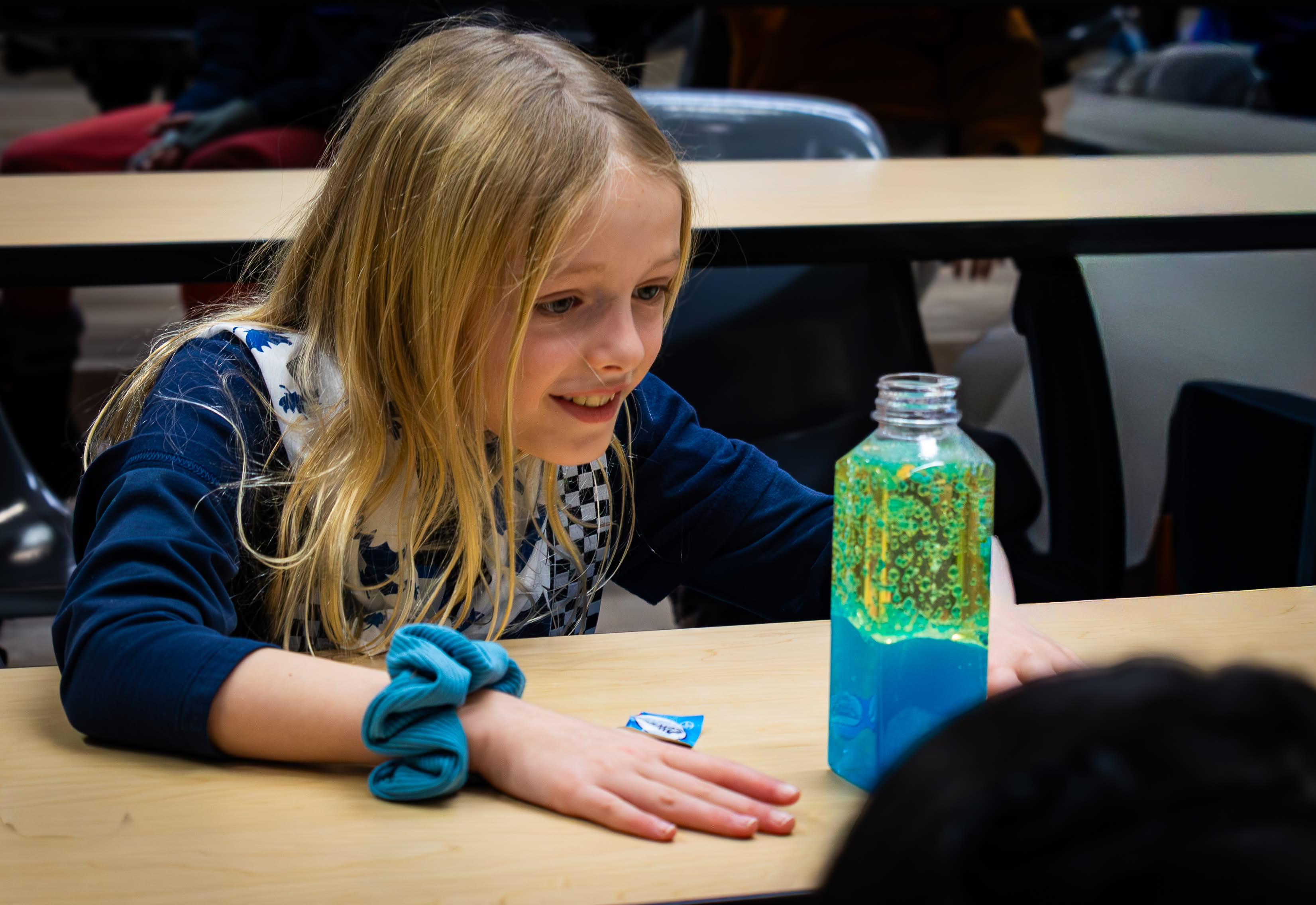 A Girl Guide smiling and looking at a bright blue lava lamp.
