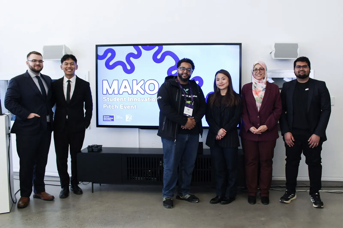 Dr. Narjes Allahrabbi smiling and standing with award recipients at the Innovation Boost Zone.