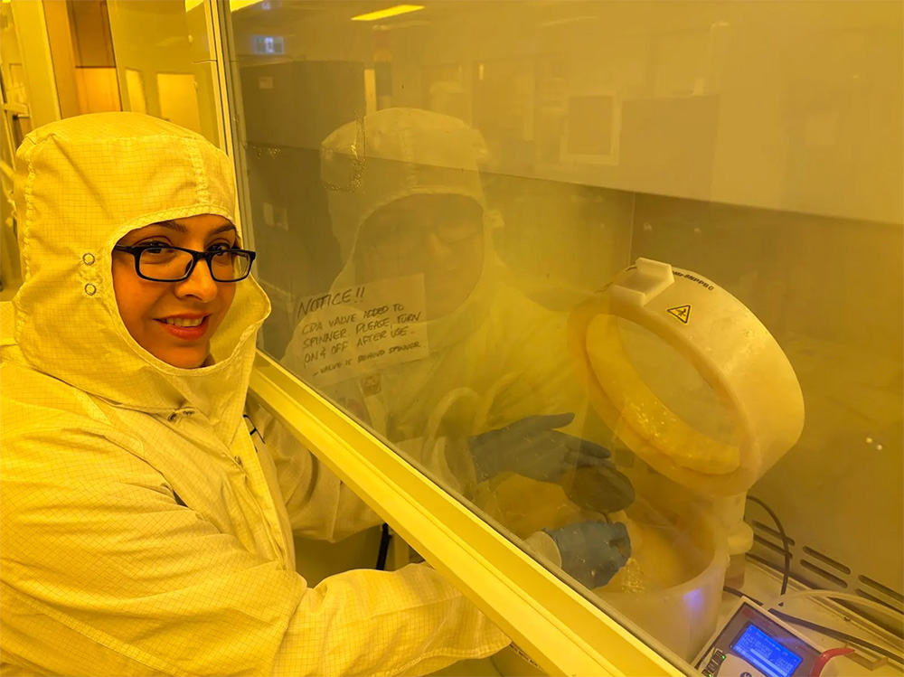 Dr. Narjes Allahrabbi in a white coveralls working in a lab.