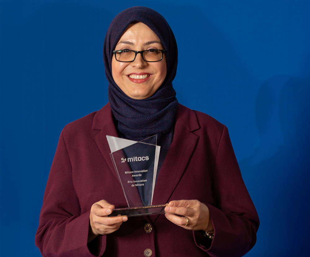 Dr. Narjes Allahrabbi holding a glass Mitacs award.