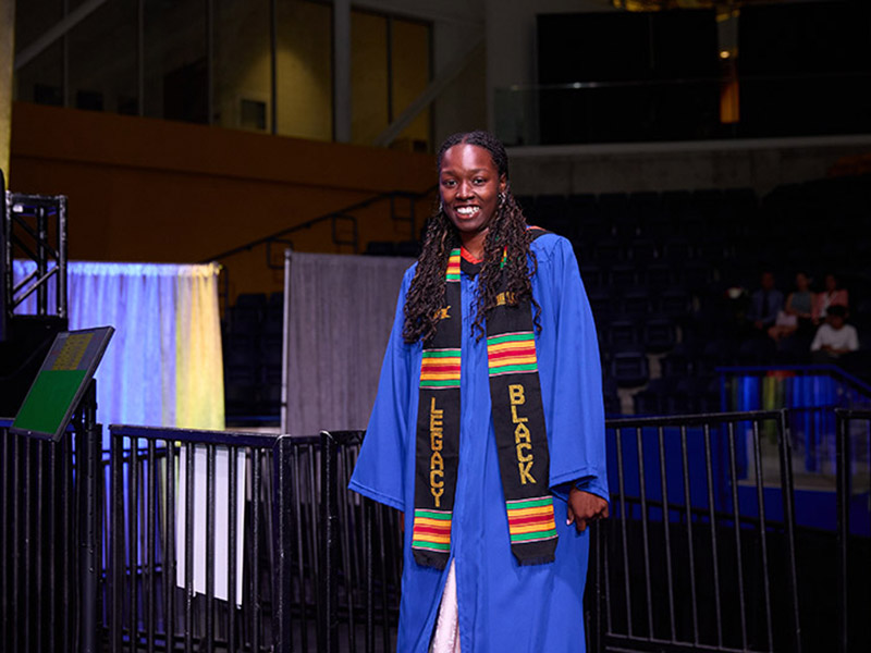 Joella Russell wearing blue convocation robe with Legacy Black sash. 