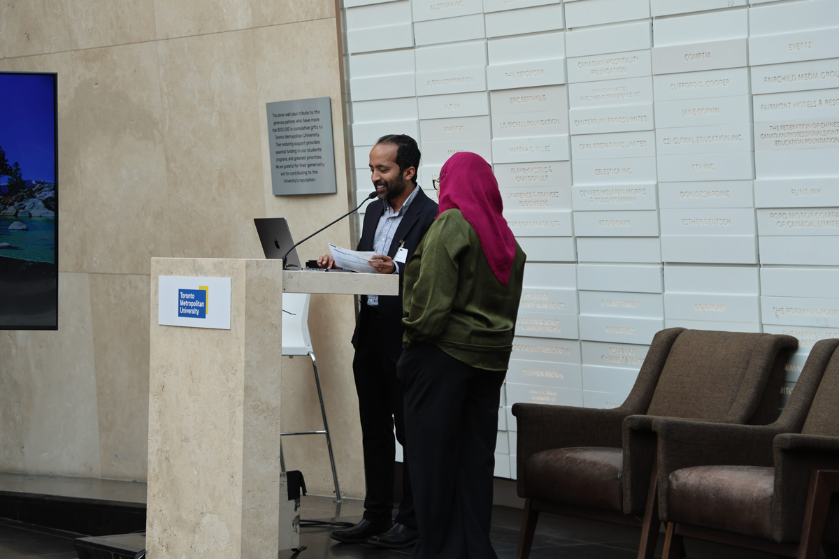 Anatoliy Gruzd presenting to audience with TV screen.