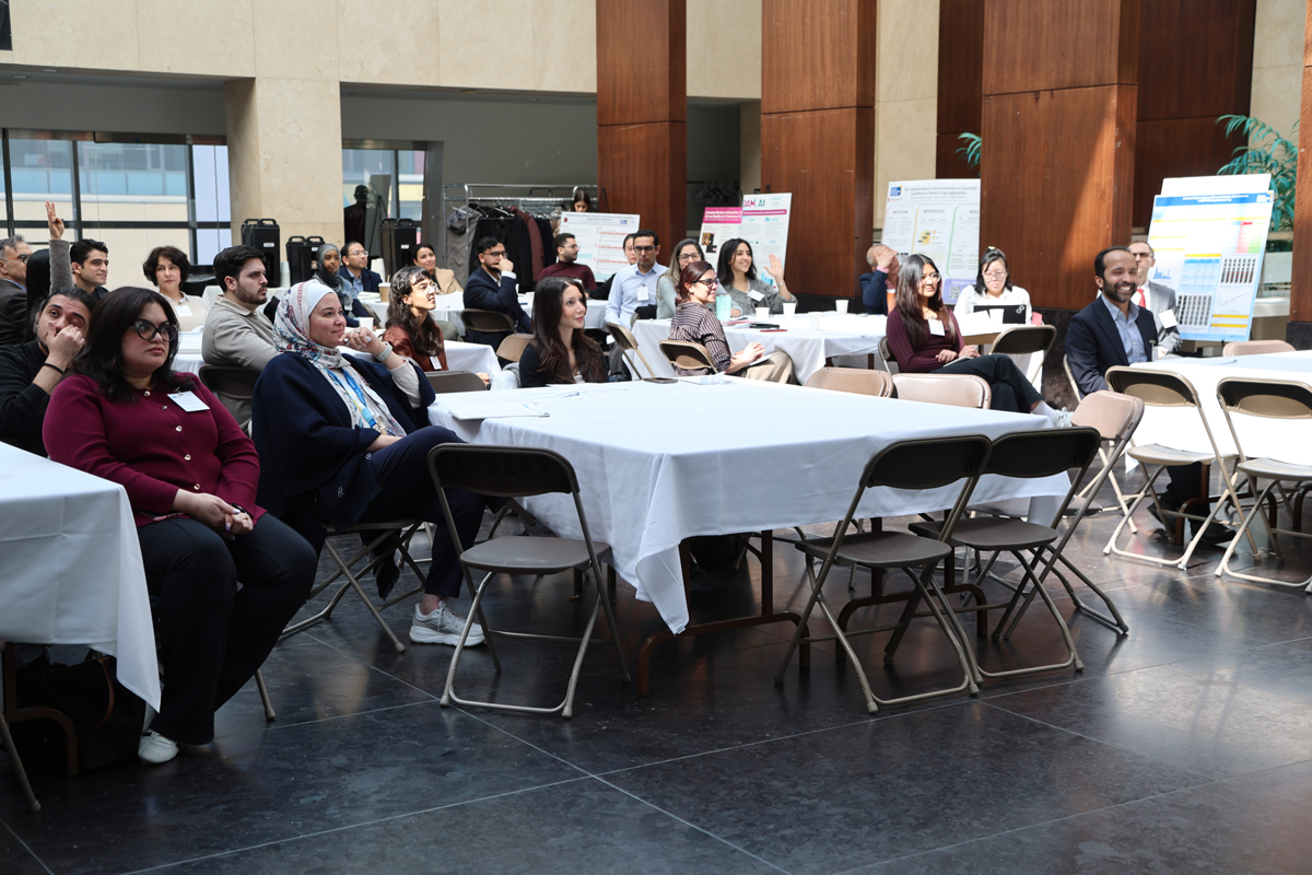 Group of attendees sitting in an atrium with beams of sunshine coming from skylight. 