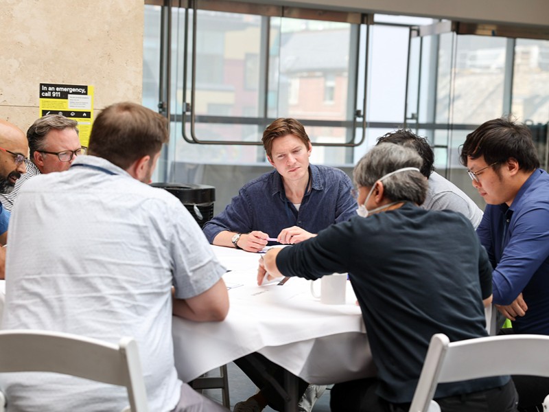 An event attendee collaborates with peers around a table during a breakout session.