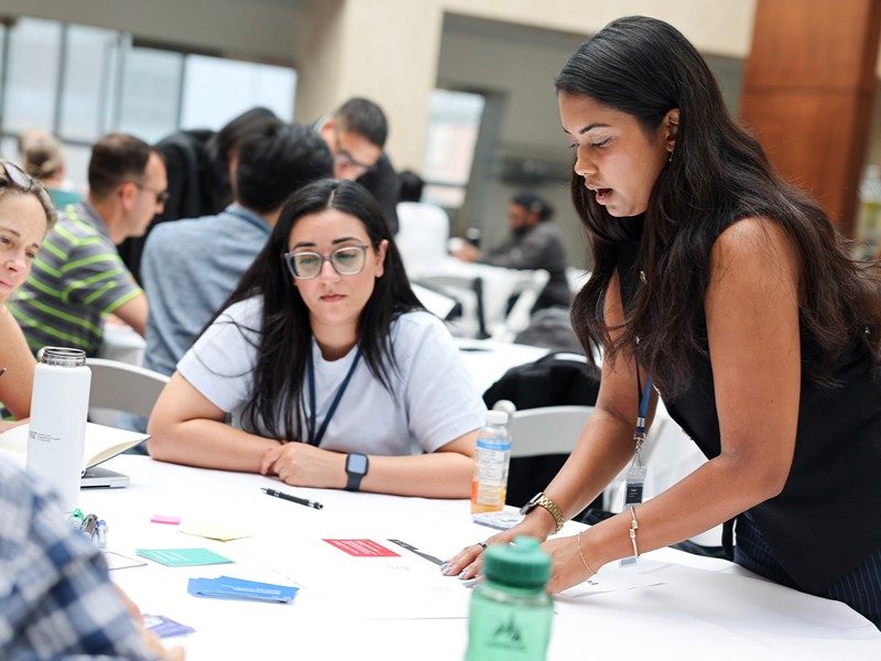 Actua staff assists attendees seated at a table during a breakout session.