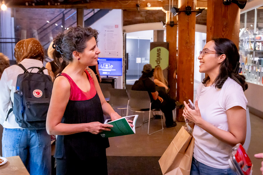 Two people having a conversation at Stripe Design, holding a copy of Women Changing Architecture.