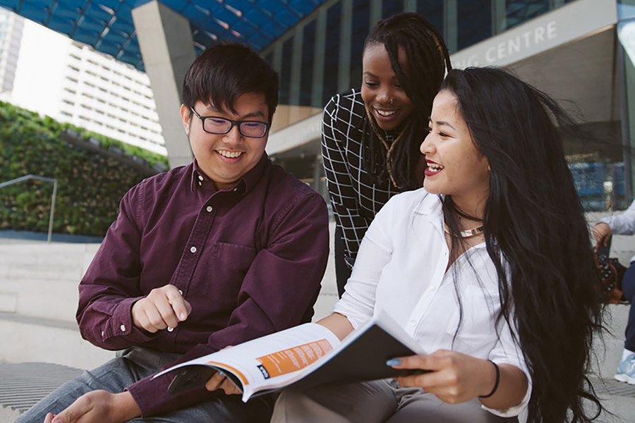 Three students on the staircase in front of the Student Learning Centre