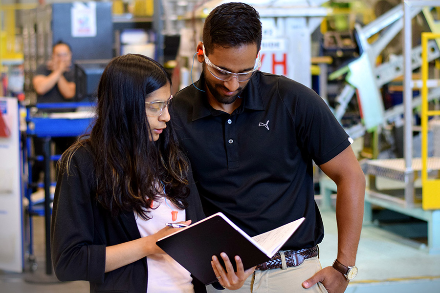 A woman and man discuss a document inside an industrial building