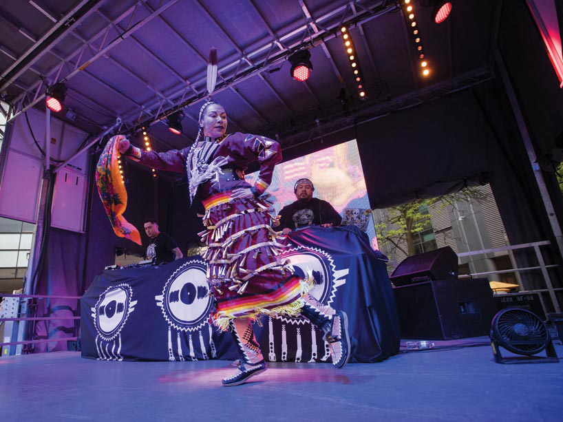 An indigenous woman dancing on stage