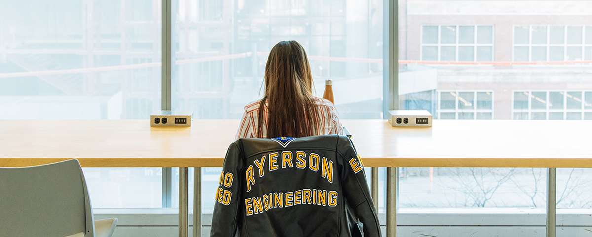 A woman with a Toronto Metropolitan University Engineering jacket studying