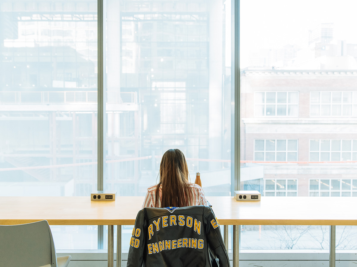 A woman with a Ryerson Engineering jacket studying