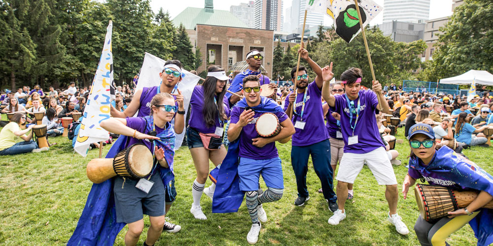 Students in purple holding instruments and dancing in the Kerr Quad