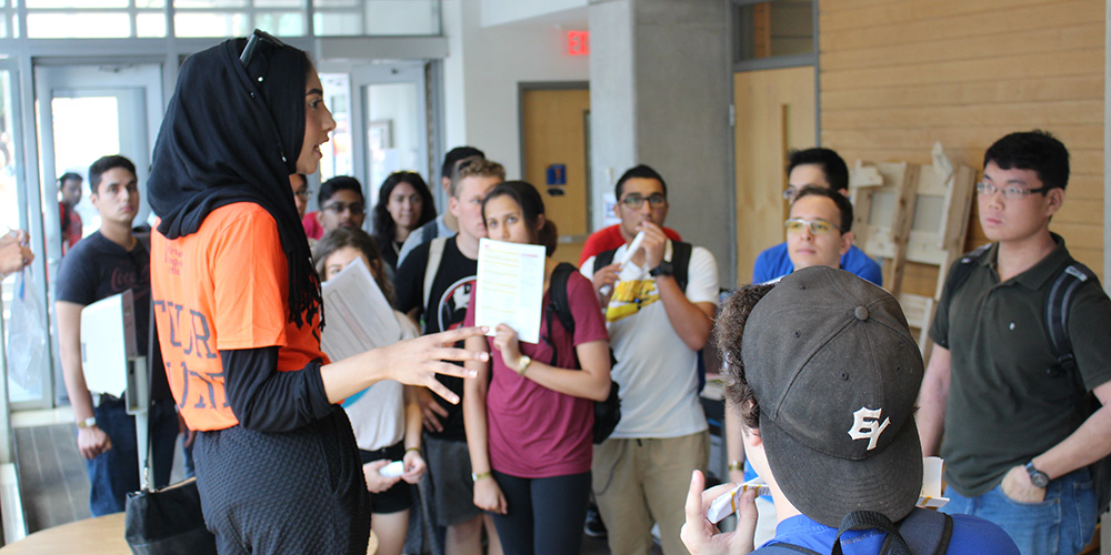 A female University tour guide addresses a crowd of students and parents