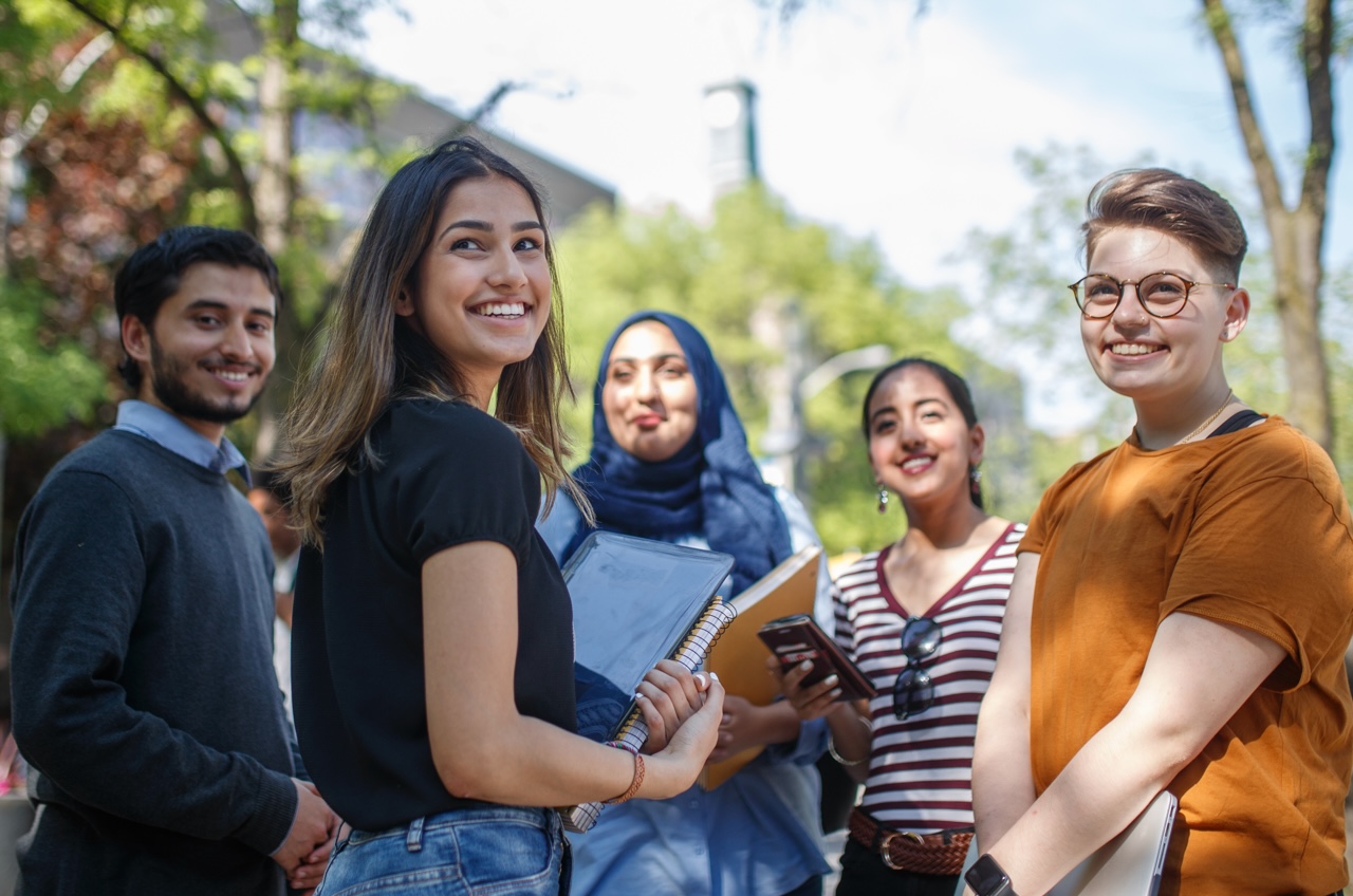 Five students standing in a group on Gould St. smiling at the camera