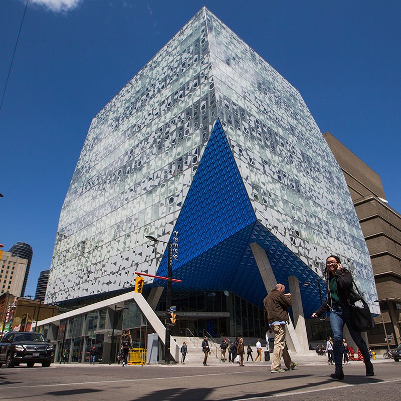 A photo of Toronto Metropolitan University's Student Learning Centre, and some students walking by it