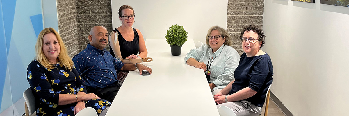 Seated on the left side of the table in the Staff and Faculty Wellbeing Lounge are: Mary Green, Sri Pathmanathan and Kelly Campbell. Seated across them are Heather Willis and Leanne Sachs.