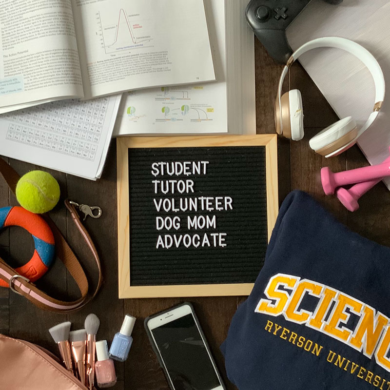 words in capital letters: STUDENT, TUTOR, VOLUNTEER, DOG MOM, ADVOCATE in white lettering on a black background in a wooden frame.