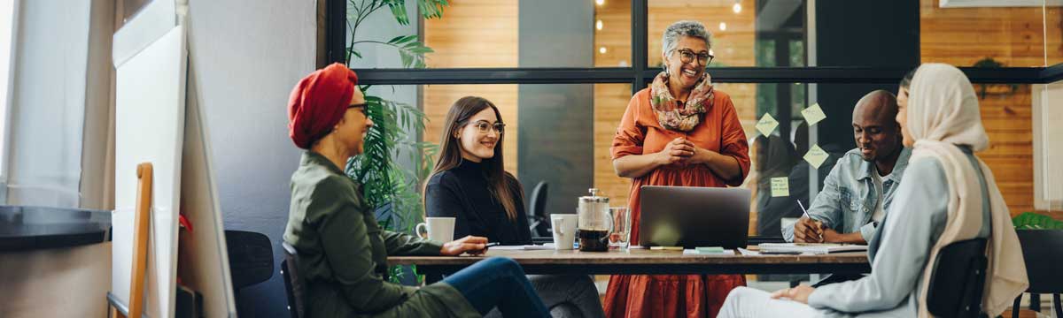 five diverse people at a table talking