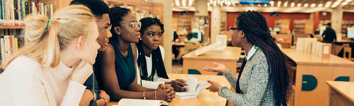 A Black women sitting at a table talking to a group of people