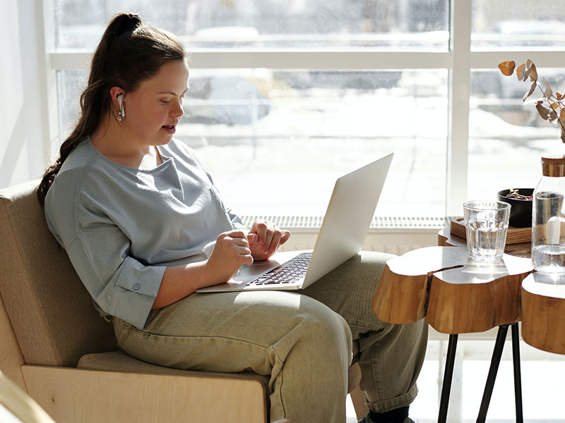 Woman with autism sitting on a couch working on a laptop.